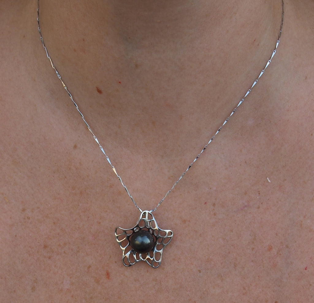 Collier fleur argent 925 orné d'une perle de Tahiti noire présenté sur nacre polynésienne