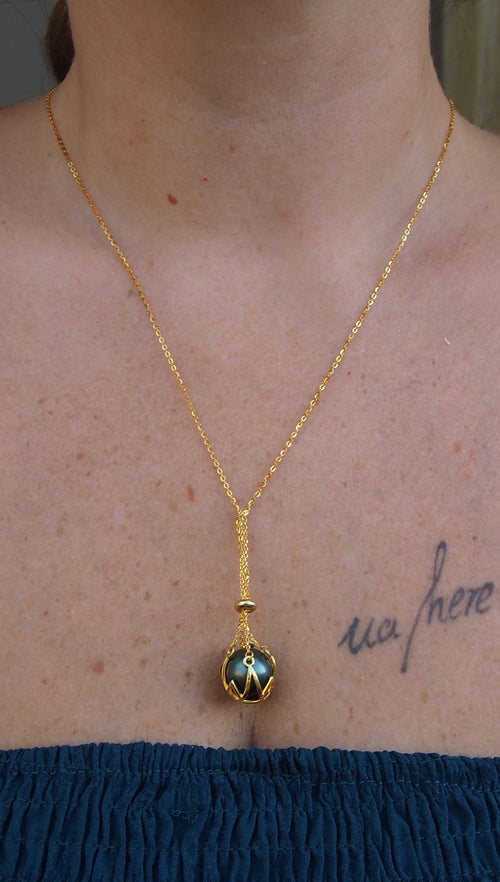 Femme portant le collier UA POU en plaqué or mettant en valeur une authentique perle de Tahiti multicolore non percée